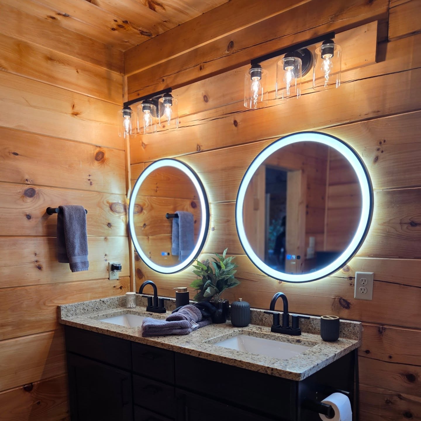 Backlit LED round mirrors with three-pendant fixture in pine bathroom