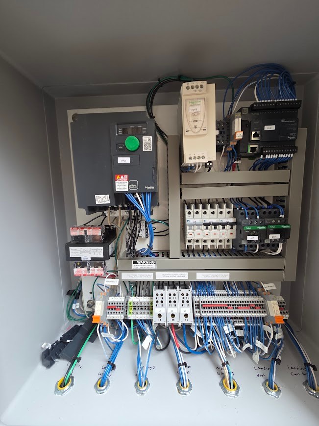 Industrial control panel with VFD, PLC, contactors and labeled terminals
